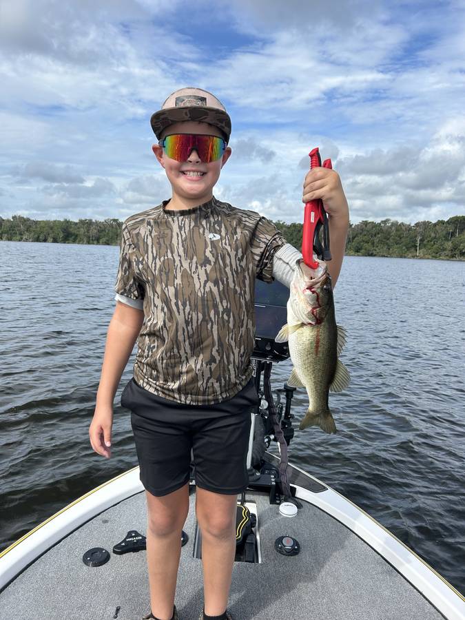 Young angler with a nice largemouth bass on a bluebird day