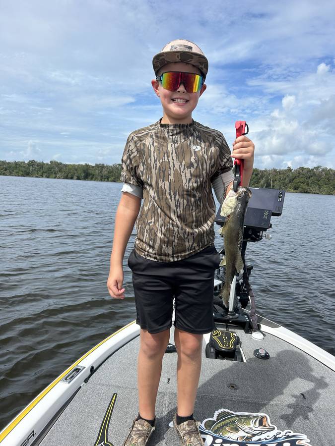 Young angler showing off his catch from the bow of the boat